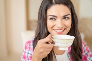 smiling-brunette-girl-drinks-coffee-from-cup-restaurant-while-looking-sideways-flirting
